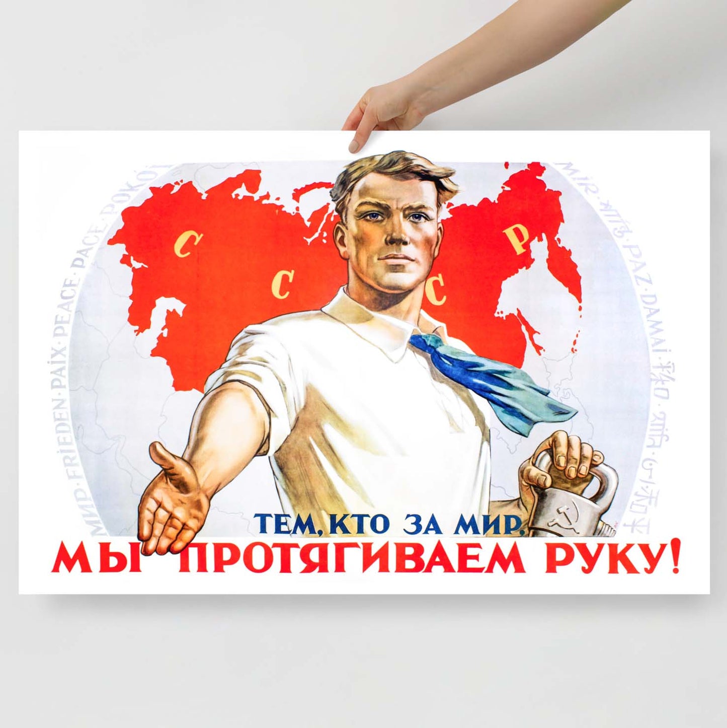 Soviet propaganda poster with a strong worker in a white shirt, standing before an atlas with “Peace” written in 13 languages.