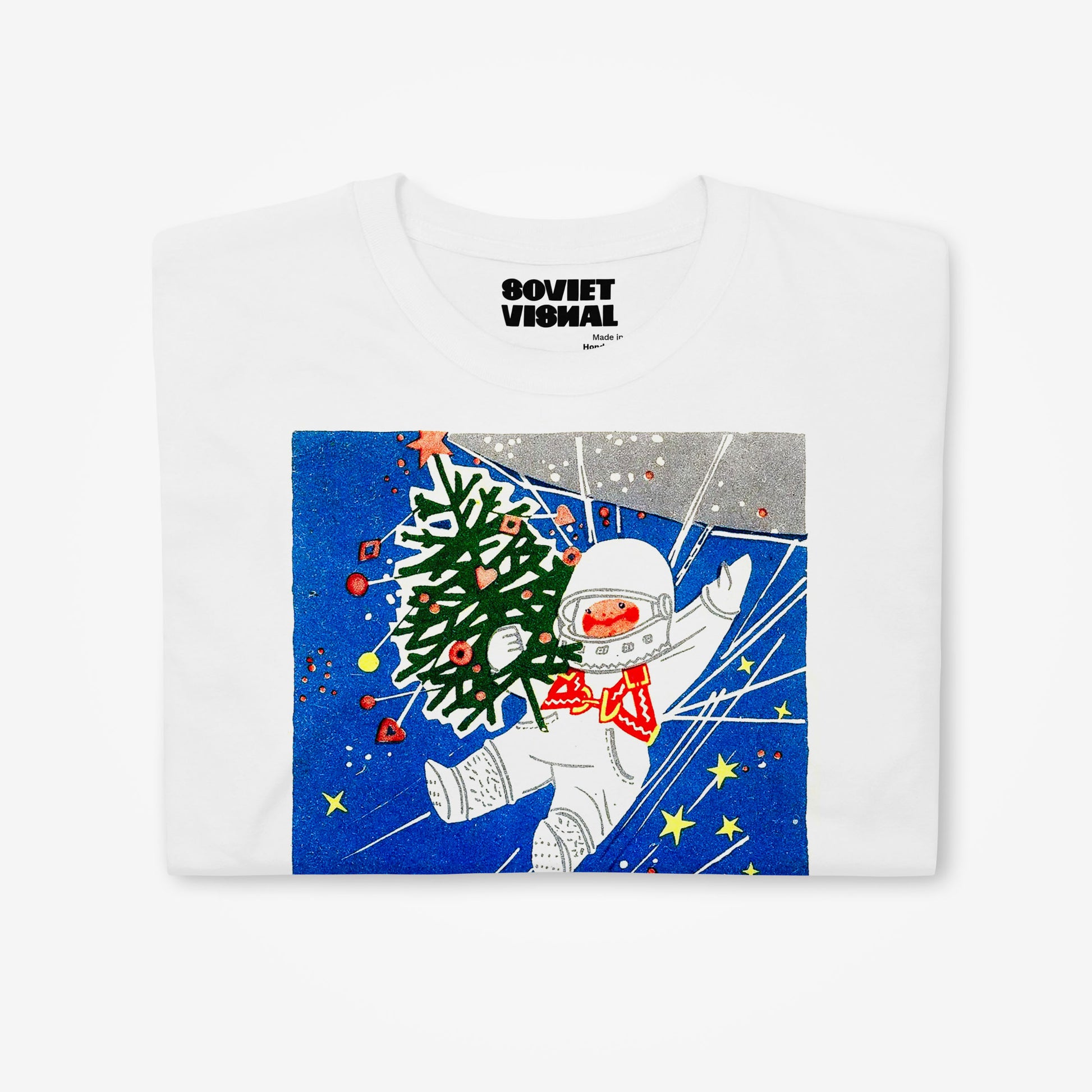 white unisex t-shirt with a young cosmonaut kid in space holding a christmas tree - folded tshirt