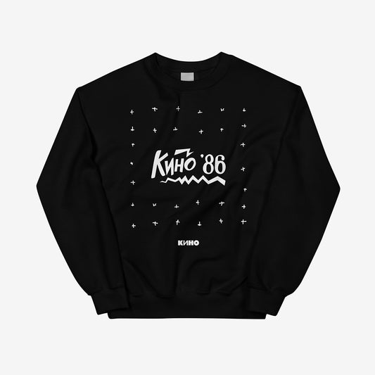 Minimalist "Любовь это не шутка" album artwork featuring a drawn Kino'86' and a small KINO logo underneath the graphic printed on the front of a heavyweight black unisex sweatshirt with a KINO logo on the back neck side, from GruppaKino.com.