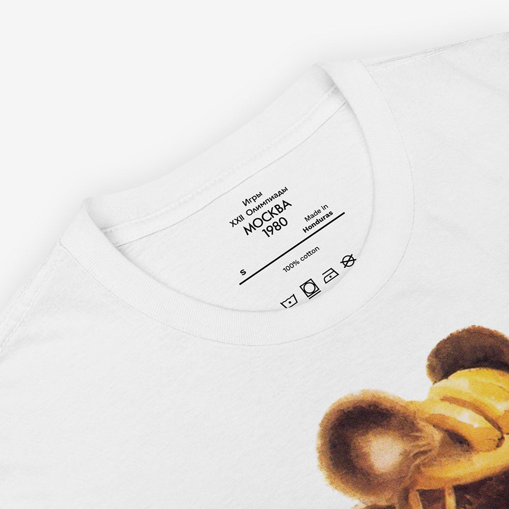 White unisex T-shirt with Misha the Bear cycling, rare Moscow 1980 Olympic mascot illustration.